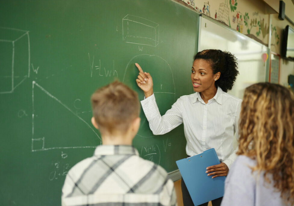 African American teacher explaining geometry to schoolkids during a class at elementary school.